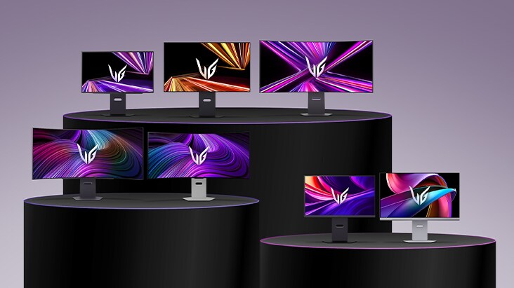 A lineup of LG UltraGear monitors in different sizes and designs displayed on tiered black podiums, each screen showing vivid abstract graphics in purple, orange, and pink tones.