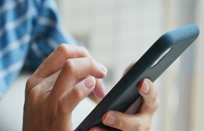 Person using a smartphone to access and control smart fridge functions remotely through the LG ThinQ app