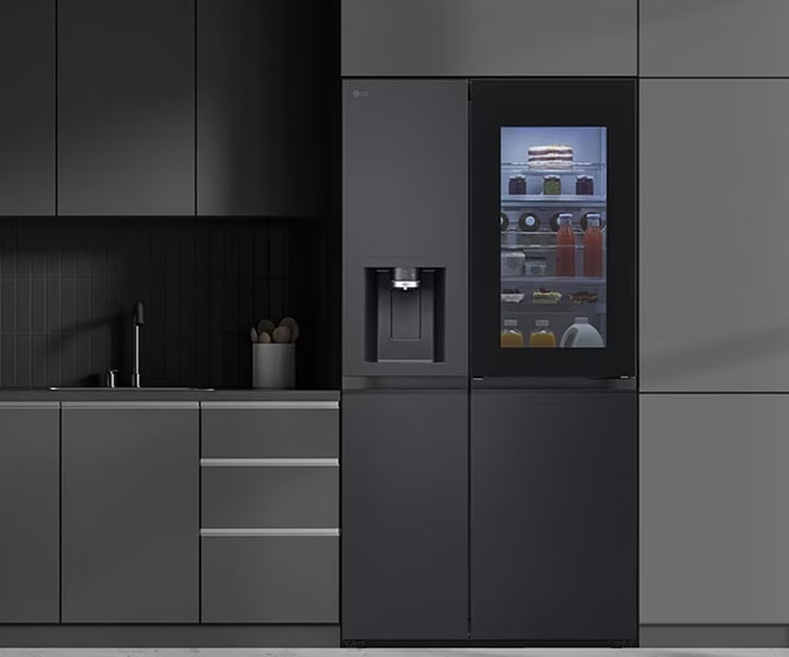 LG InstaView smart refrigerator in a modern kitchen interior showing illuminated glass door and built-in water dispenser