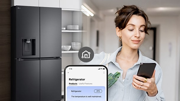 Person checking LG ThinQ app on smartphone to monitor and adjust refrigerator temperature while returning home with groceries	