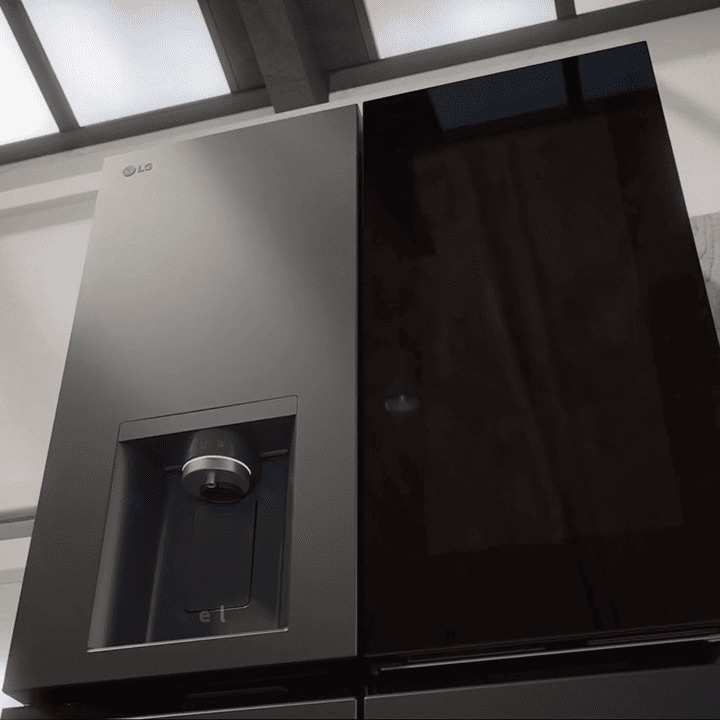 Close-up of LG InstaView refrigerator. The see-through panel lights up, followed by the water dispenser. The sleek handle is shown before the door opens.