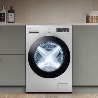 A white LG washing machine is neatly installed under a laundry counter. Inside the drum, water sprays from four directions during the washing process.