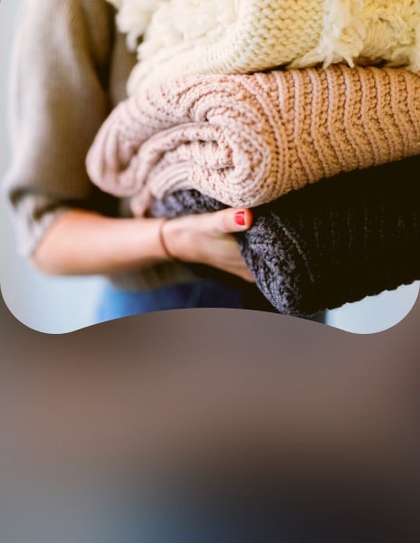 Person holding neatly folded knitted clothes after drying with LG smart dryer