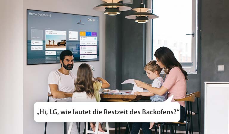 Eine Familie sitzt am Tisch und die Mutter fragt den Fernseher nach der Restzeit des Backofens.