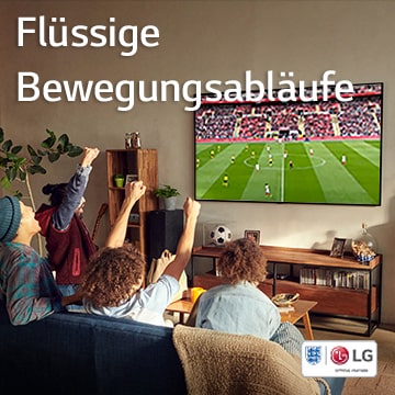 Vier Personen sitzen in einem Wohnzimmer auf einer Couch und sehen sich ein Fußballspiel an.