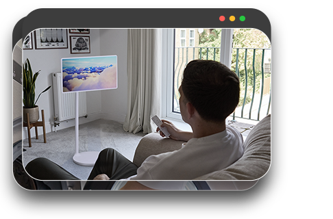 Mann entspannt sich auf dem Sofa und schaut sich Inhalte auf einem Monitor in einem gemütlichen Wohnraum an.