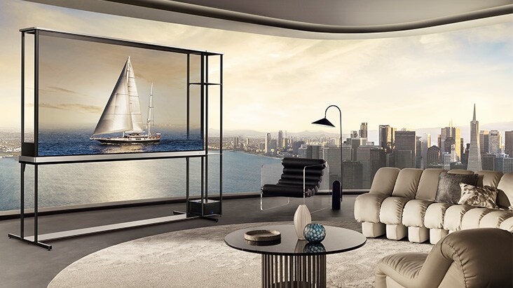 LG OLED T4 in a penthouse apartment. The windows overlook a city skyline and ocean. The LG OLED T4 is in transparent mode displaying an image of a yacht. Because of the position of the TV and the screen's transparency, the yacht looks like it's floating on the ocean outside.	