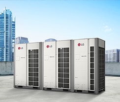 Three LG MULTI V i units stand side by side on a rooftop, front-facing view, against a backdrop of assorted tall and short buildings. 