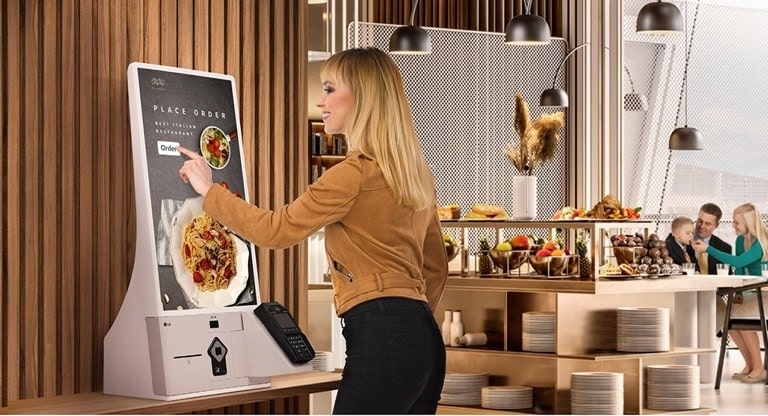 A woman is ordering food at a kiosk in a family restaurant.