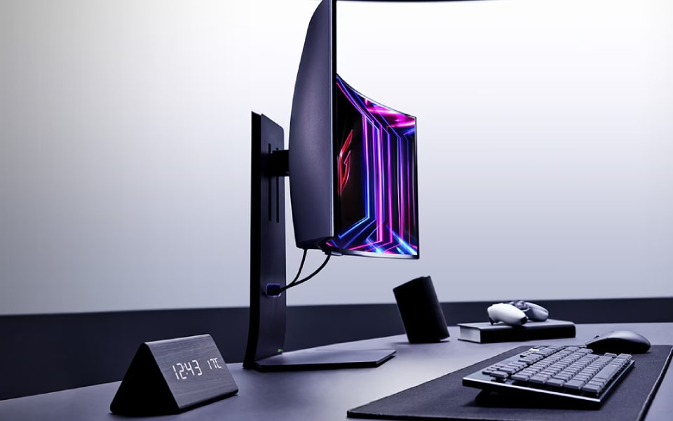 A modern desktop setup features a LG Curved Gaming Monitor with vibrant colours, a keyboard, a mouse, and an angled clock displaying the time. The setup is minimalistic and professional.