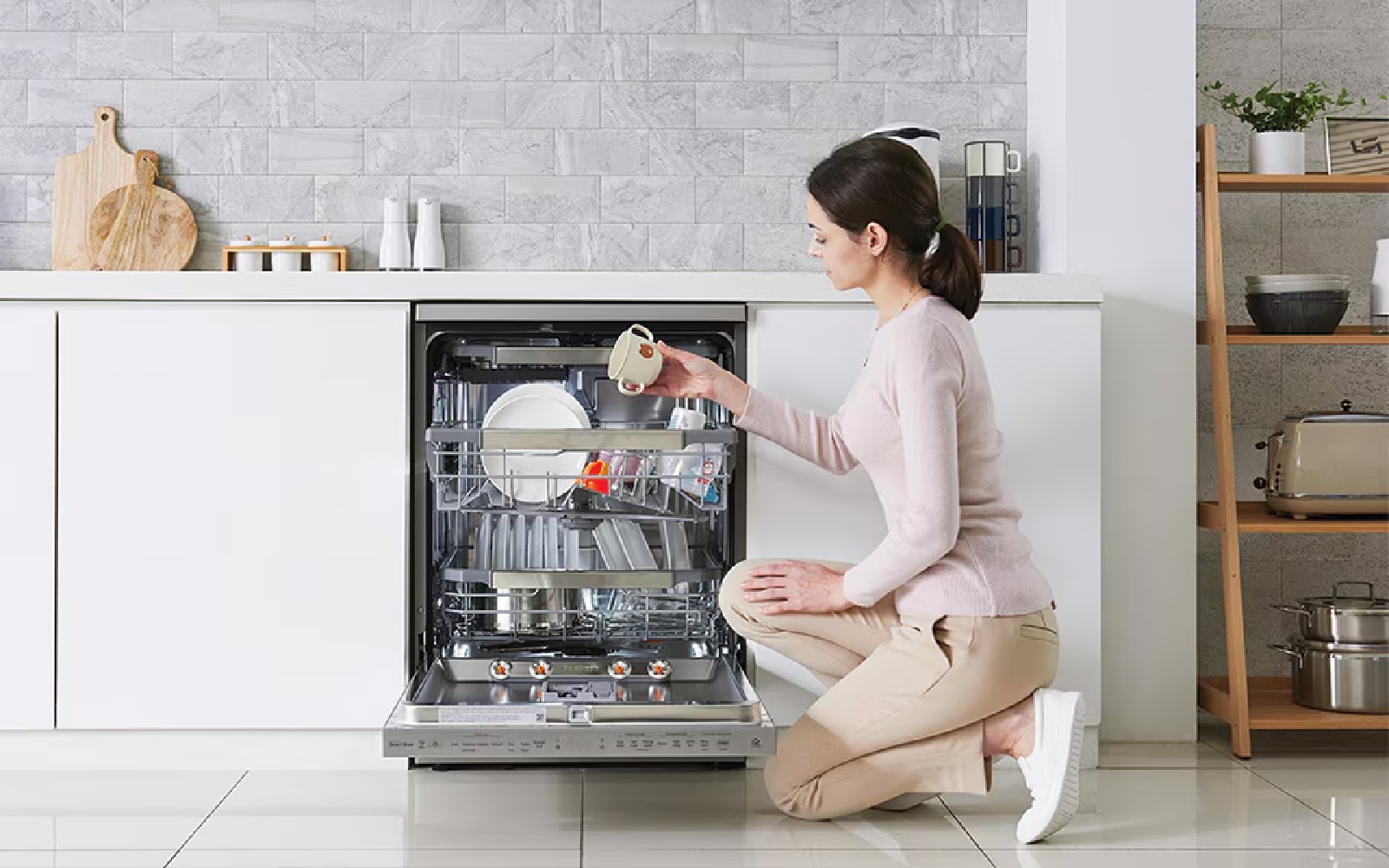 Woman loading a dishwasher with kitchenware, emphasising easy-to-use, efficient dishwashing technology.