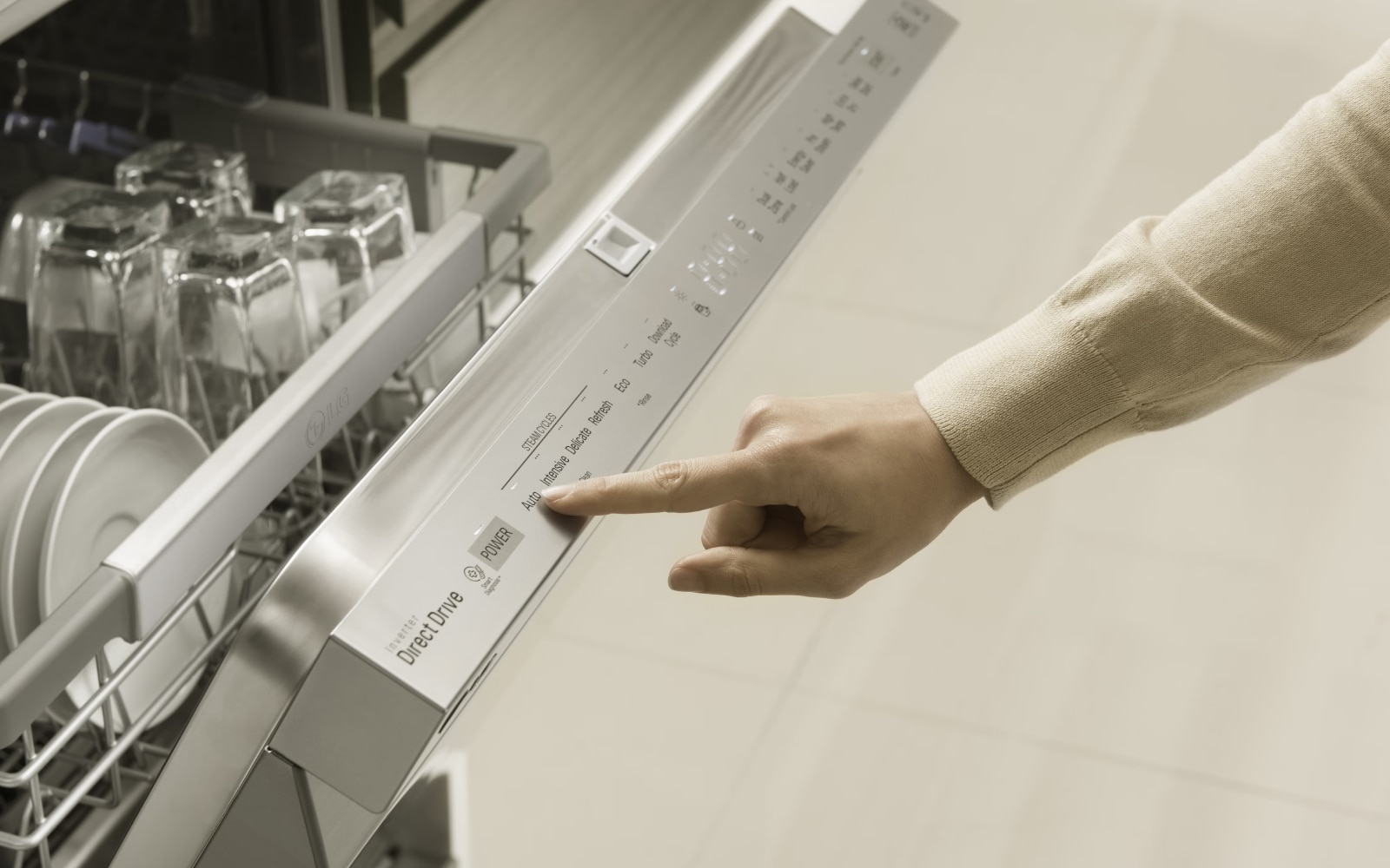 A close-up image of a person's hand pressing a button on the control panel of a stainless steel dishwasher. The dishwasher door is slightly open, showing clean dishes inside.