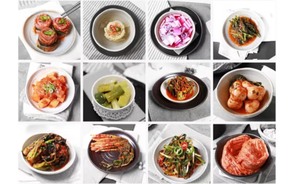 12 bowls of various kimchi and pickled vegetables, showcasing a colourful assortment of Korean side dishes.