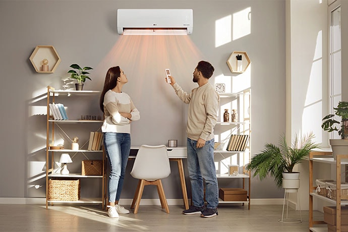 A man and a woman are blown by a warm wind in front of a heater