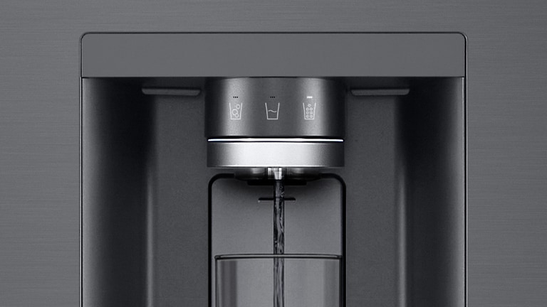 A video starts zoomed in on the water dispenser. The exterior of the refrigerator goes clear and now the interior of the door and mechanical parts of the dispenser nozzle can be seen. The video zooms in further to show the water droplets as they fall through the UVnano part of the nozzle which reduces the bacteria. The view zooms back out to see the exterior of the refrigerator again as water is being dispensed into a glass.