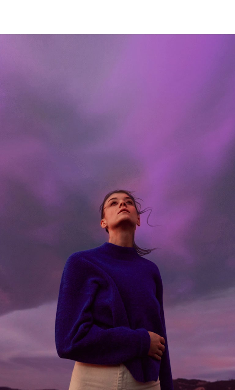 A woman is looking at a purple sky. Her hair is slightly shaking.