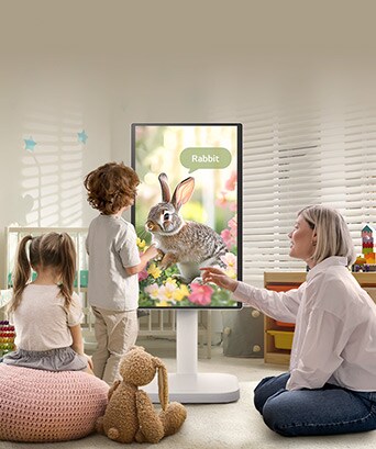 This picture shows a woman and three children playing using a LG Smart Monitor Swing.
