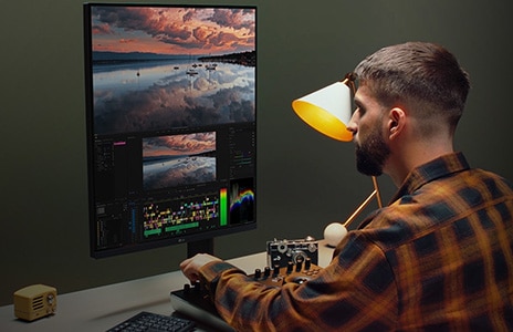 Man works at desk in front of ergo monitor on video editing software