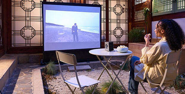 Uma hóspede assiste a um filme projetado em uma tela com o CineBeam.