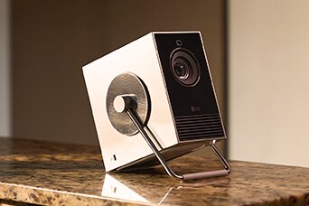 Projetor LG CineBeam sobre a mesa, demonstrando uso sem fio com bateria externa.