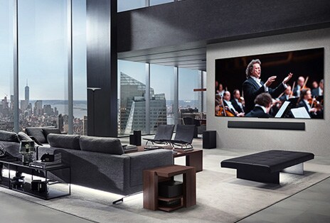 Sala de estar com uma LG True Wireless TV e uma LG Soundbar montada na parede. A Zero Connect Box mal pode ser vista sob uma mesa lateral ao lado do sofá, mostrando como pode ser facilmente colocada em qualquer lugar. Todo o layout da sala de estar é visualmente limpo e organizado.