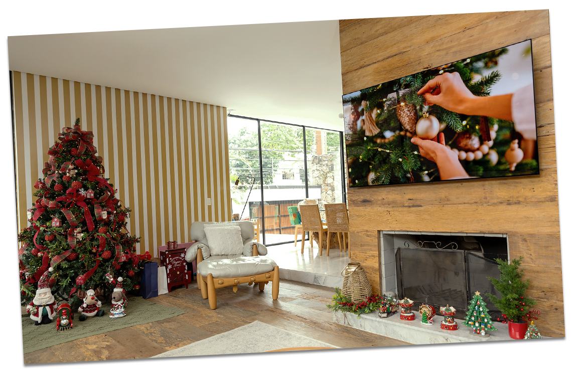 Uma árvore de Natal é decorada em um ambiente aconchegante de feriado, com uma TV LG OLED exibindo um vídeo de decoração natalina na sala de estar.