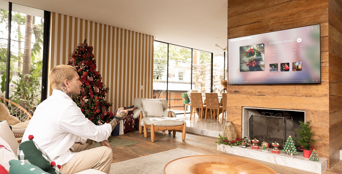 Um homem está relaxando em um sofá em uma sala de estar moderna, usando um controle remoto para controlar a TV LG OLED C4.