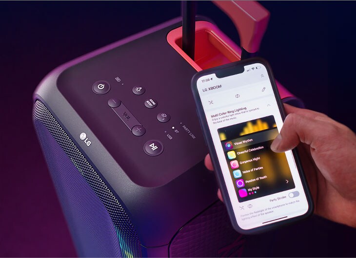 Close da caixa de som LG XBOOM com um smartphone conectado, mostrando a interface do app Thinq para controlar música e luzes.