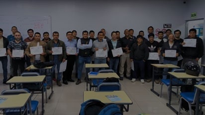 No espaço onde acontece o treinamento, diversas pessoas posam com certificados nas mãos.