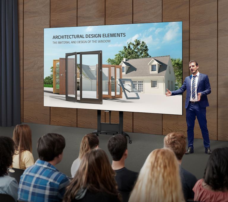 Um homem explica o conteúdo que está na tela de uma série LAEC instalada com uma base exclusiva em um auditório.