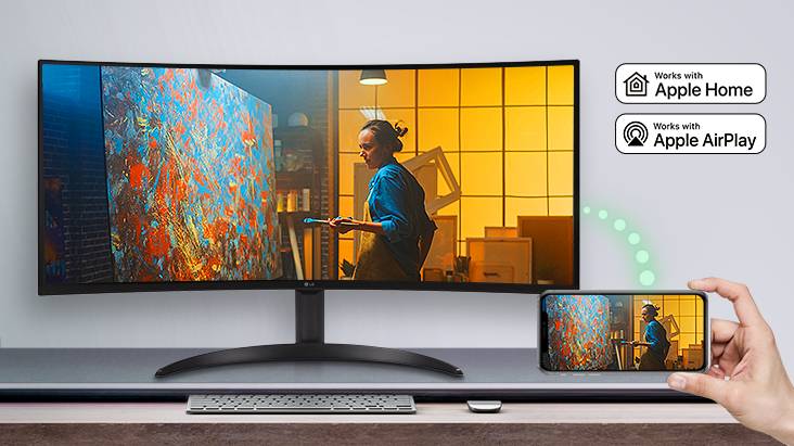 Na mesa, há um monitor exibindo uma cena de um filme, e a mesma cena é exibida em um dispositivo móvel colocado no canto inferior direito.
