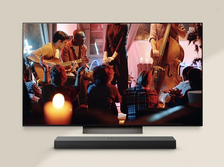 Um concerto aconchegante está passando em uma TV LG com um LG Soundbar embaixo.