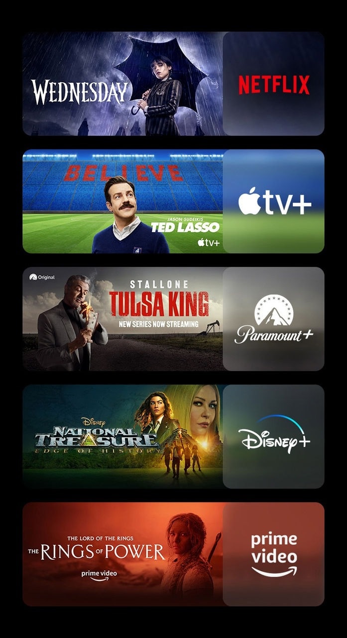 Há cinco blocos de imagem, cada um com o logotipo da plataforma de streaming e a imagem de uma cena. Logotipo Netflix com Wandinha, logotipo Apple TV plus com Ted Lasso, logotipo Paramount plus com Tulsa King, logotipo Disney plus com A Lenda do Tesouro Perdido, logotipo Prime Video com Os Anéis de Poder.