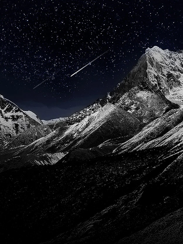 A living room space features a wall-mounted LG OLED TV displaying a mountain range against a dark evening sky filled with stars. The scene is split in half — one side shows a duller, greyer version of the landscape labelled “Non Perfect Black display,” while the other shows a more vibrant picture with a wider dynamic range of blacks and whites, labelled “Perfect Black display.” A certification logo is also visible, stating: Perfect Black Technology delivers black levels less than or equal to 0.24 nit up to 500 lux.