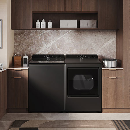 The LG Top Load Washer and Dryer set (WT8600CB) in Black Steel, showcasing its premium, side-by-side design seamlessly integrated into a luxurious laundry room with marble and wood finishes.