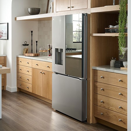 The stainless steel finish LG 36-inch 26 cu.ft. French Door Refrigerator LRYKC2606S, shown installed in a modern kitchen with light wood cabinets.