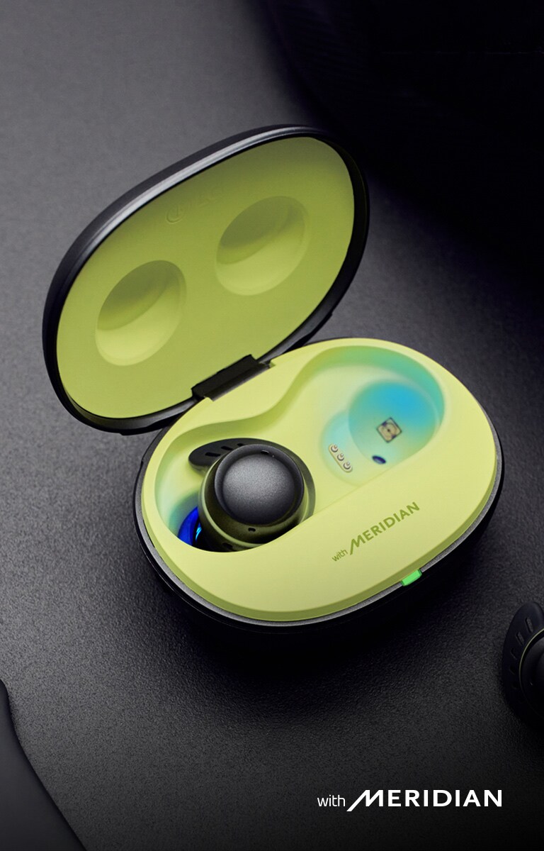 The TONE Free fit cradle is open, with the left earbud inside the cradle, and the right earbud outside. Meridian's logo is seen at the bottom of the image.