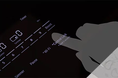 Hand activating the control lock on an LG induction cooktop, which prevents accidental use and provides added safety for households with children.