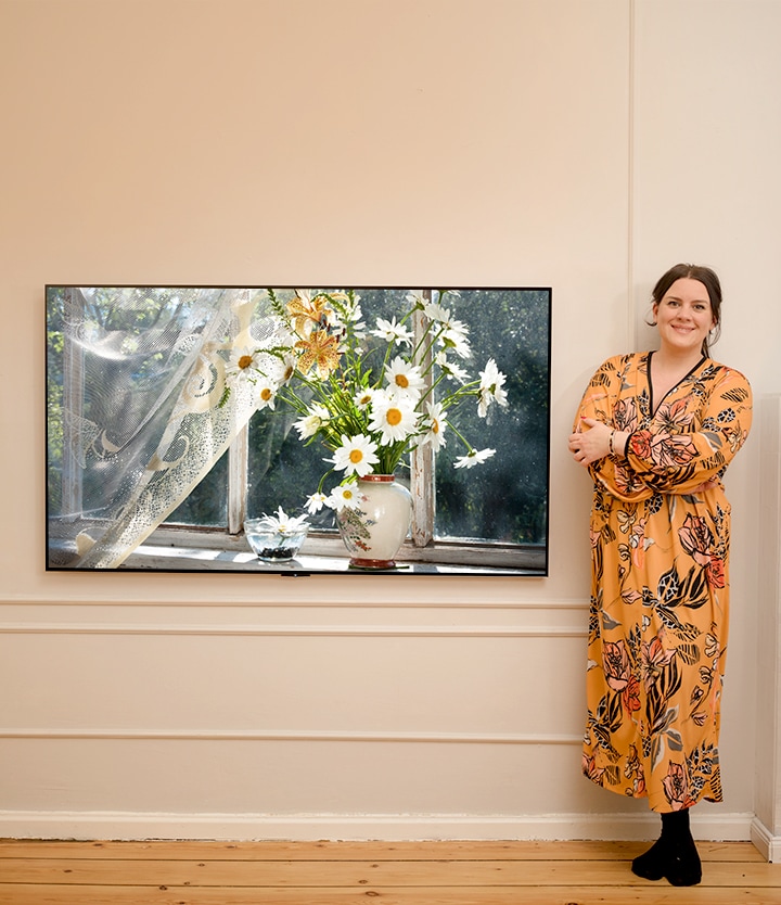 This is a video in which an image of a woman with a flower passing in front of a television and an image of a woman next to a washing machine appear in succession.