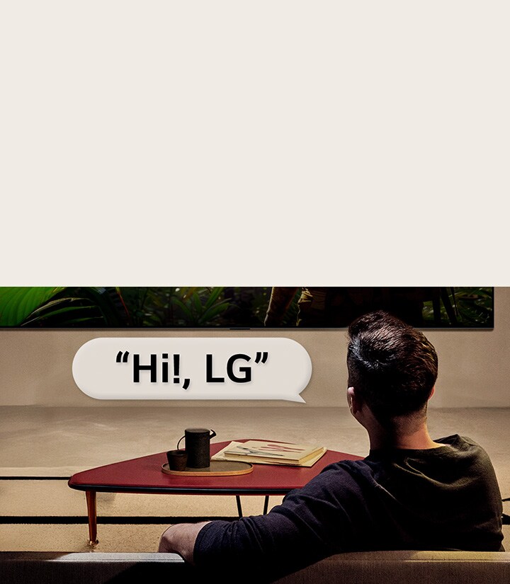 Personne dans son salon. Bulle de conversation autour d’eux montrant comment ils interagissent avec leur LG TV en disant simplement « Hi LG ».