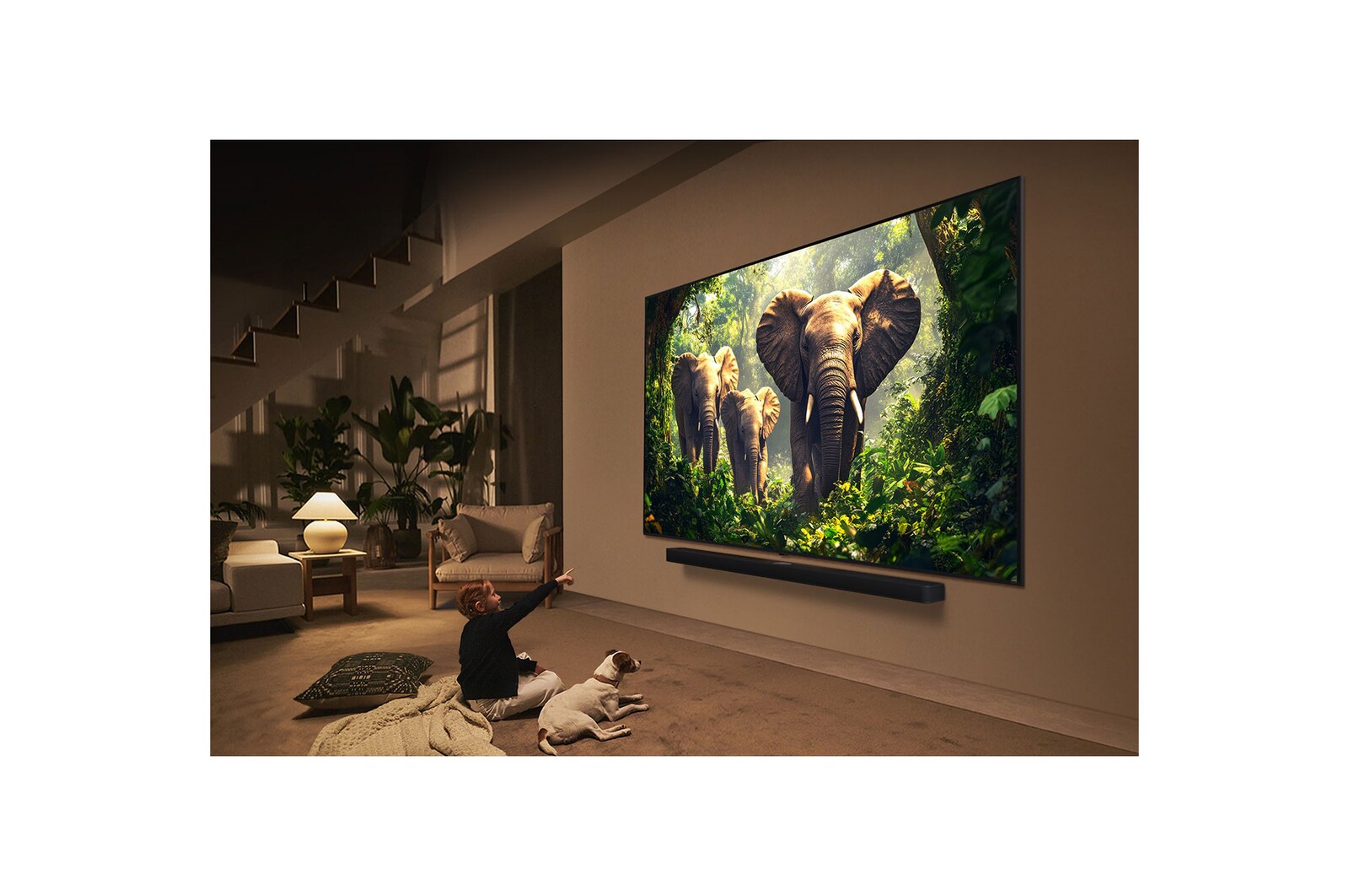 Une fille et un chien sont assis devant un LG QNED TV accroché au mur et représentant trois éléphants marchant vers l’extérieur, au-dessus d’une LG Soundbar. Le titre met en avant comment chaque action devient plus captivante sur un écran géant.