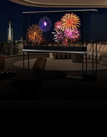 TV transparente LG affichant des feux d’artifice éclatants dans un salon luxueux en hauteur la nuit, avec la silhouette de la ville visible en arrière-plan.