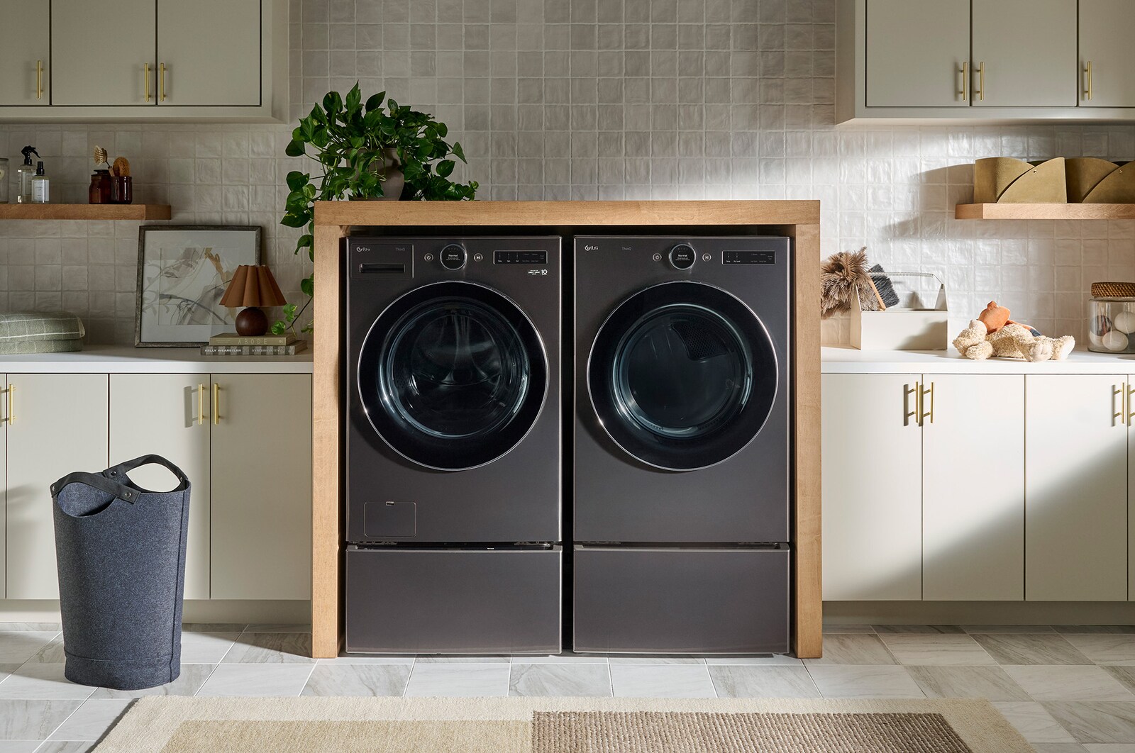 L'ensemble lave-linge et sèche-linge frontal LG (WM6700HBA) en Noir Acier, présentant une installation côte à côte élégante sur des socles, intégrée dans un mobilier moderne.