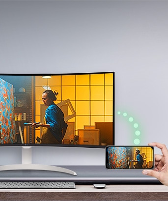 Un moniteur est posé sur la table, et à droite, un téléphone affichant le même écran que le moniteur est visible.