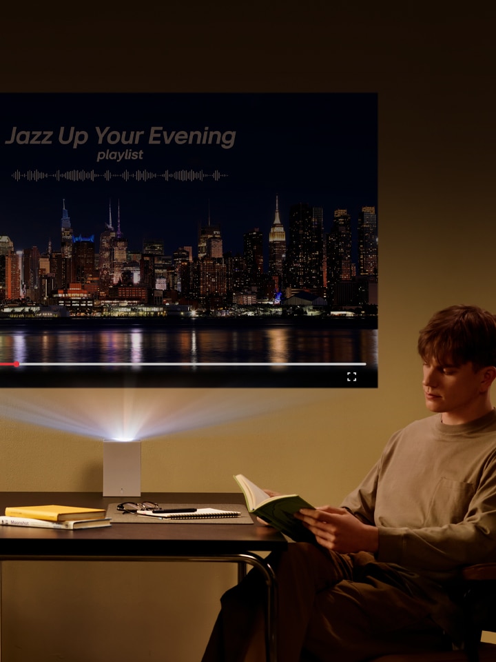 Homme lisant un livre avec un projecteur LG CineBeam en arrière-plan.