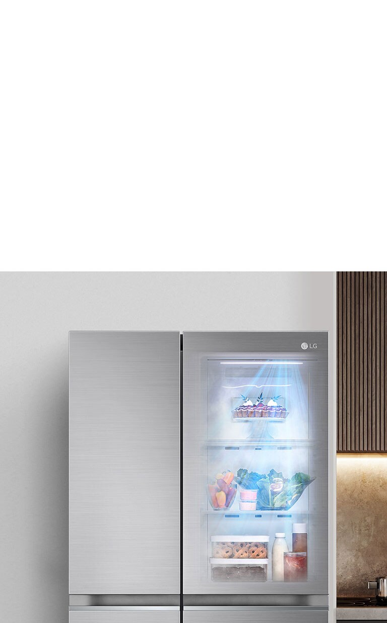 Réfrigérateur LG avec porte transparente à gauche, aliments frais visibles à l'intérieur, cuisinière à droite.