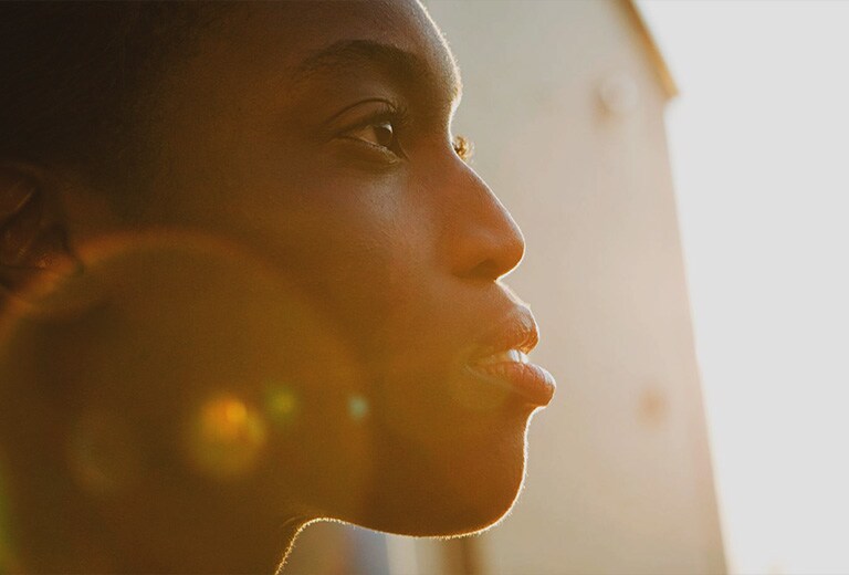 Une femme regarde vers le soleil.