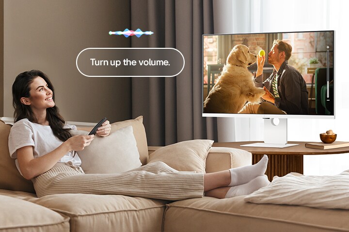 Une femme augmente le volume du LG Smart Monitor à l’aide du Magic Remote.