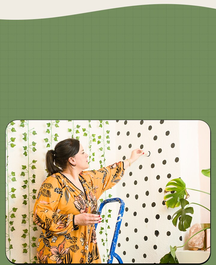 La femme décore en peignant des points sur le mur.
