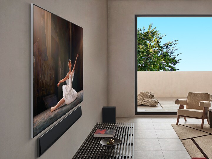 Un salon dans une maison haut de gamme. Vue latérale inclinée d’une LG OLED TV murale. On voit qu’il n’y a aucun gap entre la TV et le mur. 
